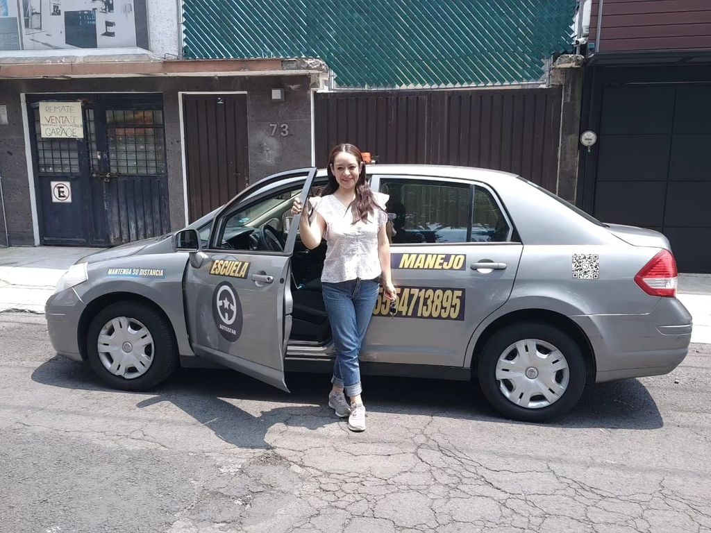 Persona junto a un sedán gris de AUTOSTAR estacionado frente a una casa